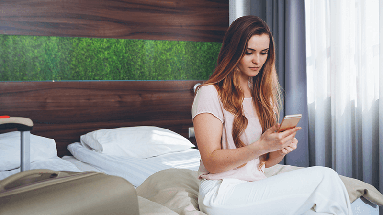 mujer sentada en una cama con el móvil